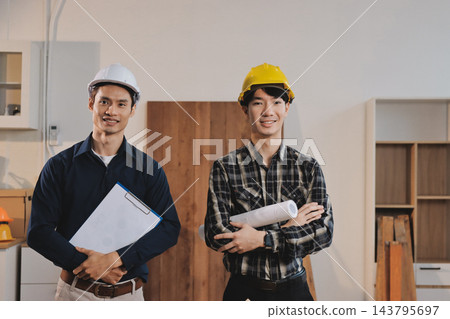 Asian architect and engineer team checking architectural house model using measuring tape on the table at office studio. 143795697