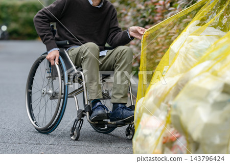 一位坐在輪椅上的老人在丟垃圾 143796424