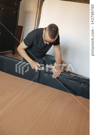 man using a ratchet on a lift-up storage bed man using a ratchet on a lift-up storage bed 143796780