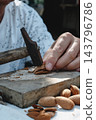 close-up of a man cracking an almond with a hammer 143796786