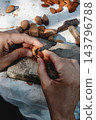man extracting an almond from its broken shell 143796788