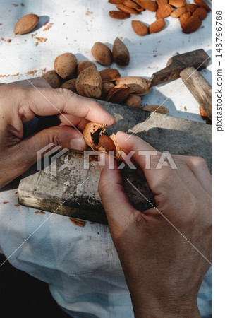 man extracting an almond from its broken shell man extracting an almond from its broken shell 143796788
