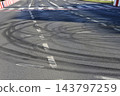 Black tire skid marks on an asphalt city road intersection 143797259