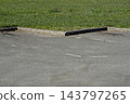 Concrete curbs in a parking lot next to a green grass lawn 143797265