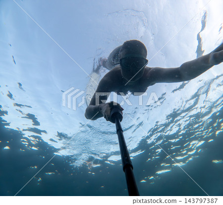 Clear sea exploration captured by young woman taking underwater selfie with monopod Clear sea exploration captured by young woman taking underwater selfie with monopod 143797387