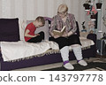 grandmother is reading colorful book grandson, has leaned in closer to listen. grandmother wearing glasses, boy, dressed red T-shirt, is intently examining the book and listening to the story. 143797778