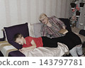grandmother is reading colorful book grandson, has leaned in closer to listen. grandmother wearing glasses, boy, dressed red T-shirt, is intently examining the book and listening to the story. 143797781