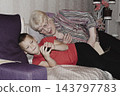 grandmother is reading colorful book grandson, has leaned in closer to listen. grandmother wearing glasses, boy, dressed red T-shirt, is intently examining the book and listening to the story. 143797783