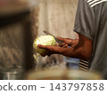 Close up of cook or vendor hands slicing fresh white cabbage on cutting board in Indonesian street food stall kitchen 143797858