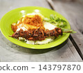 Sate ati ampela or fried duck liver and gizzard skewer served with steamed rice, tempeh, serundeng, and sambal on a green plate 143797870
