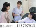 A young elementary school girl and her mother receiving an explanation about orthodontic treatment. 143797913