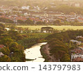 Aerial view of a river flowing through green suburban landscape and residential housing area during golden hour sunrise 143797983