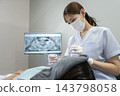 A dental hygienist checking the patient's oral cavity. 143798058