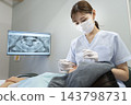 A dental hygienist checking the patient's oral cavity. 143798731