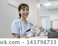 A female dental technician smiling and looking at the camera. 143798733