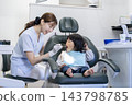 A dental hygienist checks the mouth of a 2-year-old girl. 143798785
