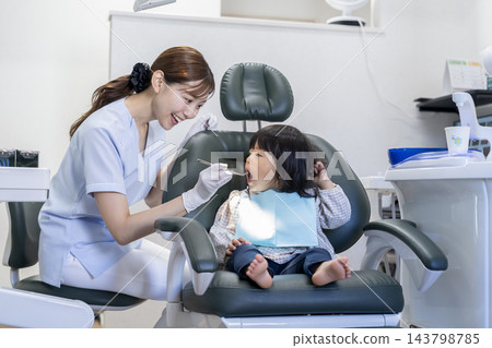 牙齒保健員正在檢查一名2歲女童的口腔。 143798785