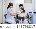 A 2-year-old girl and her mother receiving toothbrushing instruction at a dental clinic. 143798817