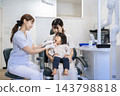 A 2-year-old girl and her mother receiving toothbrushing instruction at a dental clinic. 143798818