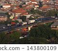 Aerial view of heavy highway traffic over elevated flyover bridge passing through dense suburban residential neighborhood 143800109