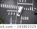 從上方俯瞰一輛白色小型貨車斜穿過十字路口，路口設有行人過街標誌和停車線。 143801529