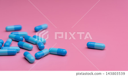 Blue capsule pills scattered on pink background with large copy space, prescription medicine and pharmaceutical treatment concept for healthcare, pharmacy, drug research and patient care. Blue capsule pills scattered on pink background with large copy space, prescription medicine and pharmaceutical treatment concept for healthcare, pharmacy, drug research and patient care. 143803539