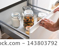 Person opening organized kitchen pantry drawer with glass food jars 143803792
