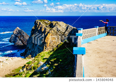 Tourist with camera on Asturias coast, Spain Tourist with camera on Asturias coast, Spain 143804048