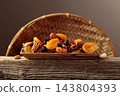 Assorted nuts and dried fruits in wooden dish. 143804393
