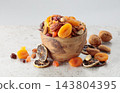 Assorted nuts and dried fruits in wooden dish. 143804395
