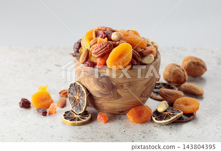 Assorted nuts and dried fruits in wooden dish. 143804395