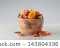 Assorted nuts and dried fruits in wooden dish. 143804396