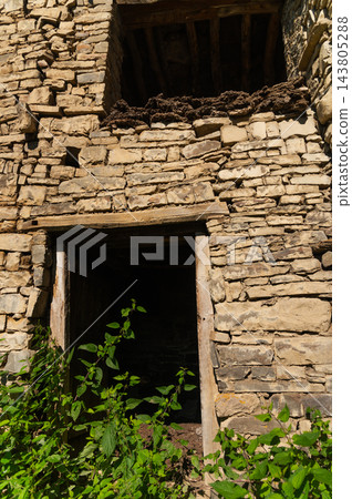Stone building ruin with wooden doorway and foliage Stone building ruin with wooden doorway and foliage 143805288