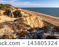 Scenic sunset view of sandstone cliffs and canyon leading to Arenosillo beach in Mazagon, Huelva, Spain. Great for travel guides, Andalusian tourism, and nature blogs. 143805324