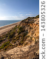 Scenic sunset view of sandstone cliffs and canyon leading to Arenosillo beach in Mazagon, Huelva, Spain. Great for travel guides, Andalusian tourism, and nature blogs. 143805326