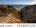 Scenic sunset view of sandstone cliffs and canyon leading to Arenosillo beach in Mazagon, Huelva, Spain. Great for travel guides, Andalusian tourism, and nature blogs. 143805328