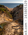 Scenic sunset view of sandstone cliffs and canyon leading to Arenosillo beach in Mazagon, Huelva, Spain. Great for travel guides, Andalusian tourism, and nature blogs. 143805329