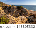 Scenic sunset view of sandstone cliffs and canyon leading to Arenosillo beach in Mazagon, Huelva, Spain. Great for travel guides, Andalusian tourism, and nature blogs. 143805332