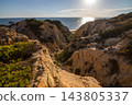 Scenic sunset view of sandstone cliffs and canyon leading to Arenosillo beach in Mazagon, Huelva, Spain. Great for travel guides, Andalusian tourism, and nature blogs. 143805337