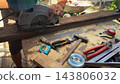 Arms of professional repairman sawing wooden construction with a circular saw at construction. Male hands of adult craftsman cuts wood using electric grind wheel at the site. Slow motion 143806032