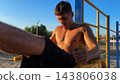 Young shirtless sportsman trains abdominal muscles raising legs on parallel bars at sports ground. Strong man exercising at nature. Sporty athlete working out at nature. Sportive lifestyle 143806038