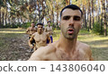 Group of young muscular athletes running at forest path. Active strong men jogging at sunny woodland. Male shirtless sportsmen training at summer nature. Concept of active and healthy lifestyle. POV 143806040