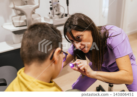 Optometrist performing eye exam on boy with cerebral palsy 143806451