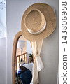 A straw hat and a scarf on a wooden-framed mirror in an interior setting 143806958