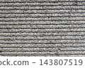 A gray, textured concrete wall. A rough background texture with a series of horizontal stripes. 143807519