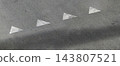 Four worn white triangle road markings pointing right on gray asphalt with a soft shadow, urban street pavement texture with copy space, high angle view and diagonal composition 143807521