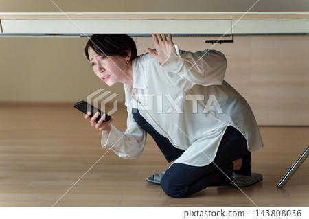 一位女士在智能手機上查看災難信息 一位女士在智能手機上查看災難信息 143808036