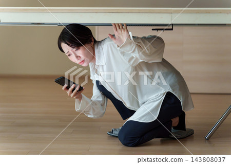 一位女士在智能手機上查看災難信息 一位女士在智能手機上查看災難信息 143808037