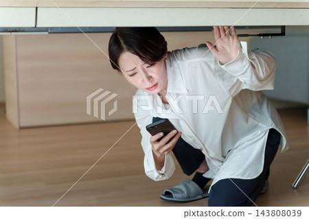一位女士在智能手機上查看災難信息 143808039