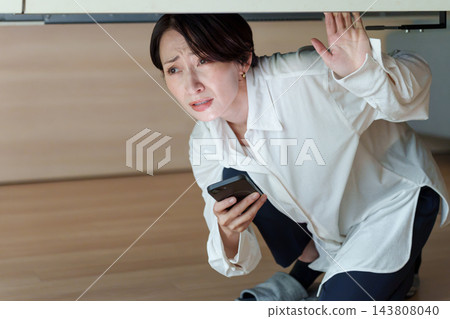 一位女士在智能手機上查看災難信息 一位女士在智能手機上查看災難信息 143808040